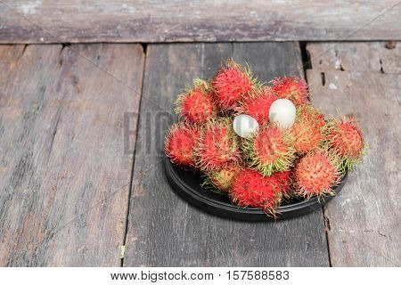 rambutan sweet fruit fresh in plate on wood background : Select focus with shallow depth of field.