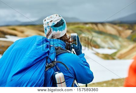 woman hiker photographer taking picture on the rhyolite mountains background in Iceland