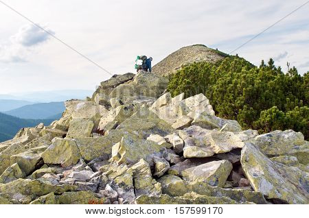 Traveler climbing to the mountain top through boulders