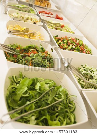 Close-up, soft focus salad bar with a variety of fresh vegetables. Colorful organic raw slice of lettuce, carrots, rukula, cucumber and pecans. Healthy eating food. (selective focus)