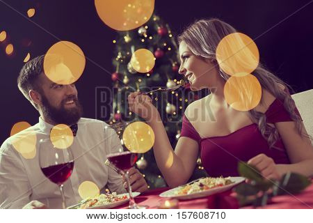 Beautiful couple sitting at a table having a romantic Christmas dinner and enjoying their time together. Focus on the girl