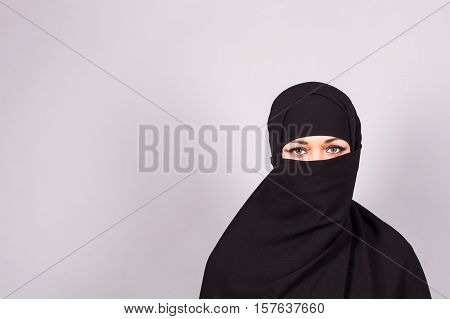 Portrait of an arabic young woman with her beautiful blue eyes in traditional islamic cloth niqab
