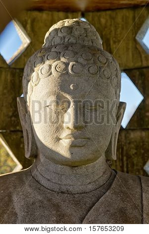 Carved stone buddha statue inside small stupa. Frontal view