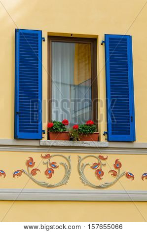 Yellow window with blue shutters in Italy