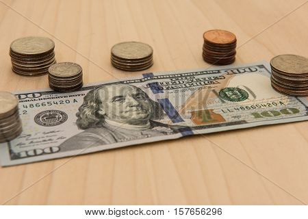 A hundred dollar bill surrounded by a stack of coins