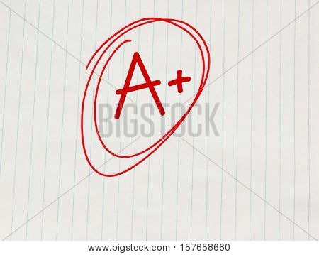 A plus (A+) grade written in red on notebook paper