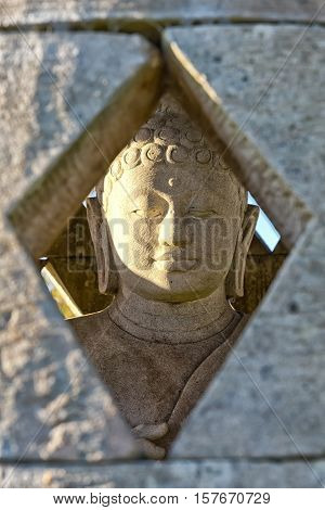 Carved stone buddha statue inside small stupa. Frontal view