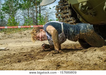 Tyumen, Russia - June 11, 2016: Race of Heroes project on the ground of the highest military and engineering school. Woman moves under tank. Caterpillar stage