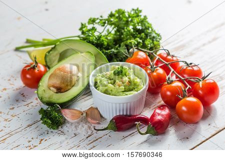 Guacamole sauce and indredients on wood background, copy space