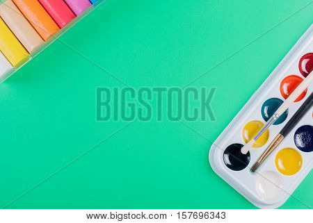 Watercolor paints and plasticine on a green background. For children's creativity