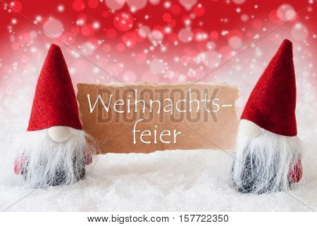 German Text Weihnachtsfeier Means Christmas Party. Christmas Greeting Card With Two Red Gnomes. Sparkling Bokeh And Christmassy Background With Snow.