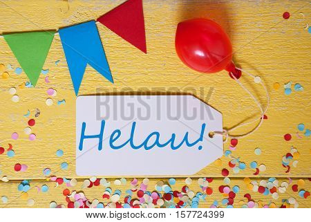 White Label With German Text Helau Means Happy Carnival. Party Decoration Like Streamer, Confetti And Balloon. Flat Lay Or Top View. Yellow Wooden Background