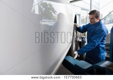 Everything under control. Professional adult mechanic changing wheel while working in auto service