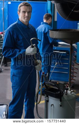 Make it the best. Positive delighted professional car mechanic holdign damper and standing in auto service while reparing car