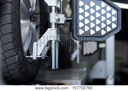 Mechanical device. Close up of car tyre clamped in alignment machine device while being checked