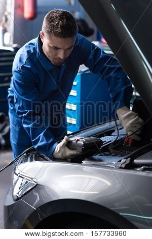 Does it work. professional mechanic holding special device and checking car engine while conducting car meintenance