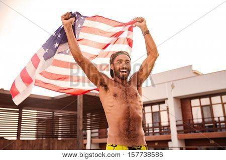 Cheerful attractive african american young man holding flag of United States