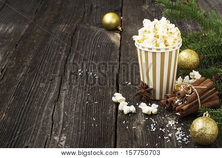 Salty fresh crusty homemade popcorn in silver paper cup in the fashion light background of white brick wall in a New Year's interior with silver Christmas balls. selective focus
