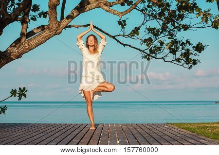 Young beautiful fitness girl with ponytail do exercises on green grass at the park.