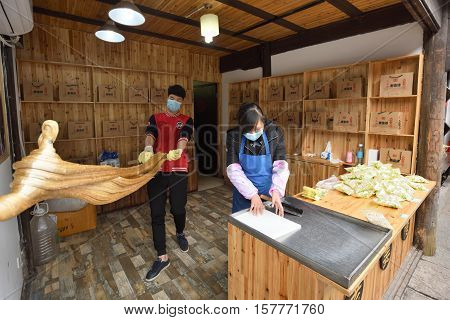 WUZHEN CHINA - MARCH 24: Unidentified Chinese people making traditional confectionery products on March 24 2016 in Wuzhen China. Wuzhen is a historic scenic town located in northern Zhejiang Province China