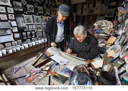 WUZHEN CHINA - MARCH 24: Unidentified Chinese artist creates traditional souvenirs on March 24 2016 in Wuzhen China. Wuzhen is a historic scenic town located in northern Zhejiang Province China