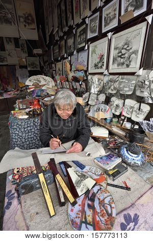 WUZHEN CHINA - MARCH 24: Unidentified Chinese artist creates traditional souvenirs on March 24 2016 in Wuzhen China. Wuzhen is a historic scenic town located in northern Zhejiang Province China