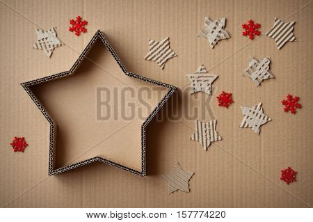 Christmas gift box in the shape of a star surrounded by decorations on cardboard background