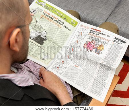 PARIS FRANCE - NOV 12 2016: Man reading Charlie Hebdo magazine on after Donal Trump elections as USA President - reading article about Daniel Ortega