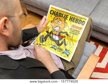 PARIS FRANCE - NOV 12 2016: Man reading Charlie Hebdo magazine on after Donal Trump elections as USA President - Barack Obama cartoon running from police officers with gun