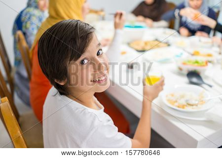 Family gathering eating meal around kitchen table