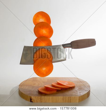 Chinese cleaver cutting carrots in the air on a white background