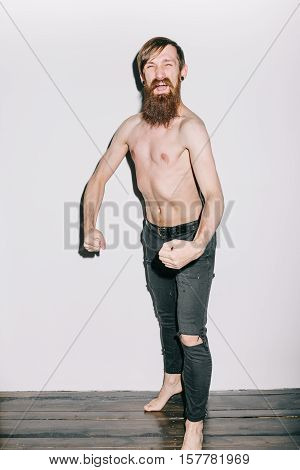 Portrait of a skinny man on a white background flexing for camera