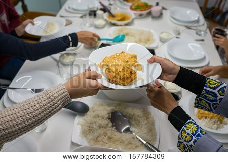 Family gathering eating meal around kitchen table