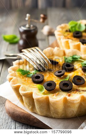 Homemade quiche tart with chicken eggplant olives and cheese on old wooden background. Selective focus.