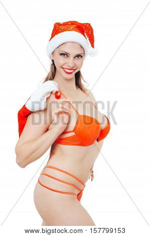 Sexy girl in red bikini and costume of Santa Claus holding a festive sock behind