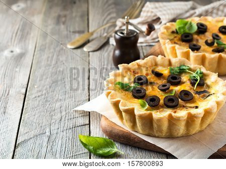 Homemade quiche tart with chicken eggplant olives and cheese on old wooden background. Selective focus.