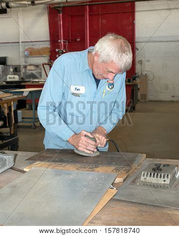 DAYTON, OHIO, USA - NOVEMBER 18, 2016: Restoration worker at the National Museum USAF is shown here buffing a piece of aluminum to be used in restoring the Memphis Belle B-17F bomber. 