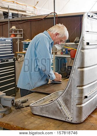 DAYTON, OHIO, USA-NOVEMBER 18, 2016:Restoration worker at National Museum USAF is shown here buffing piece of aluminum to be used in restoring the Memphis Belle's co-pilot seat, shown in foreground. 