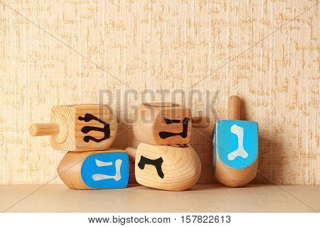 Dreidels for Hanukkah on light table against textured wall