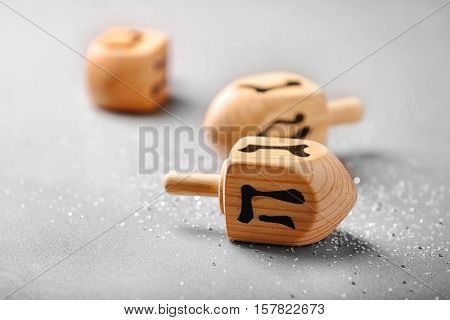 Wooden dreidel for Hanukkah on light background