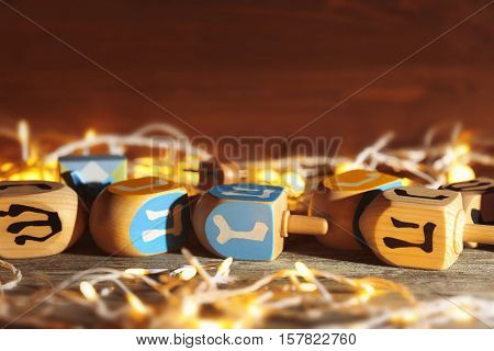 Composition of dreidels for Hanukkah and garland on wooden table