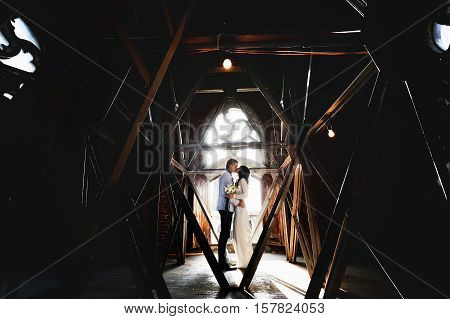 Couple kisses in the front of old Gothic window and behid the metallic gratting