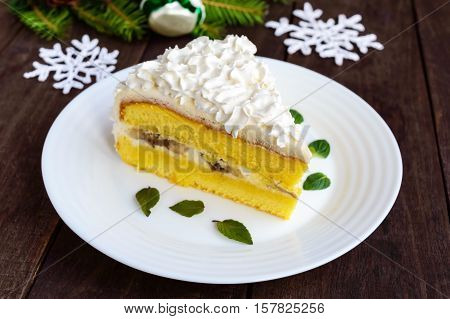 A large piece of delicate sponge cake decorating air cream. Festive dessert on a wooden background. To celebrate Christmas New Year's Eve.