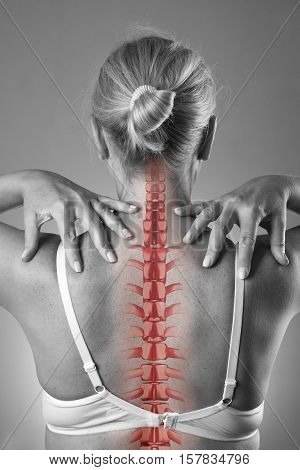 Spine pain woman with backache and ache in the neck black and white photo with red backbone on gray background