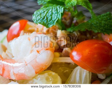 Close-up of shrimp and pomelo salad. Shallow depth of field with one shrimp pieces of pomelo and a cherry tomato in focus.