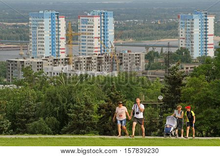 Volgograd Russia - June 24 2014: People walking on Mamaev Hill on a background of industrial construction cranes and building in Volgograd