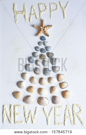 Photo by seashells in the shape of Christmas tree with congratulation of the sand.