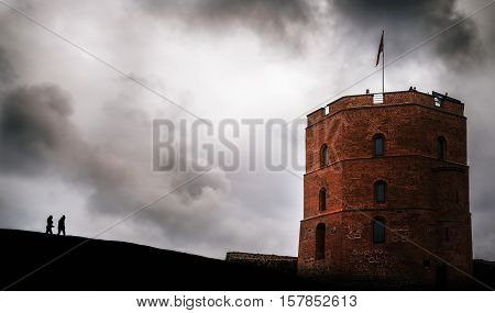 Two people silhouette go to the tower of Gediminas Vilnius Lithuania