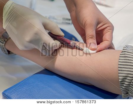 Nurse taking Real Blood samples (Phlebotomist) for analysis from a patient (Selective focus)