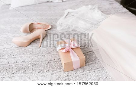 Engagement look. White amazing stunning wedding dress and shoes lying on the bed in the bedroom